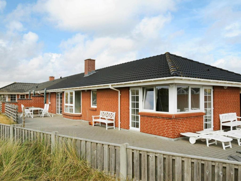 a red brick house with chairs and tables on a deck at 16 person holiday home in Hvide Sande in Hvide Sande