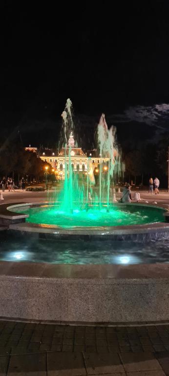 uma fonte com luzes verdes em frente a um edifício em ALES apartman em Sombor