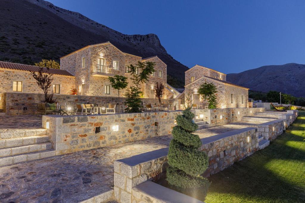 a large building with a stone wall with a yard at Salvia Areopolis All Suite Hotel in Areopoli