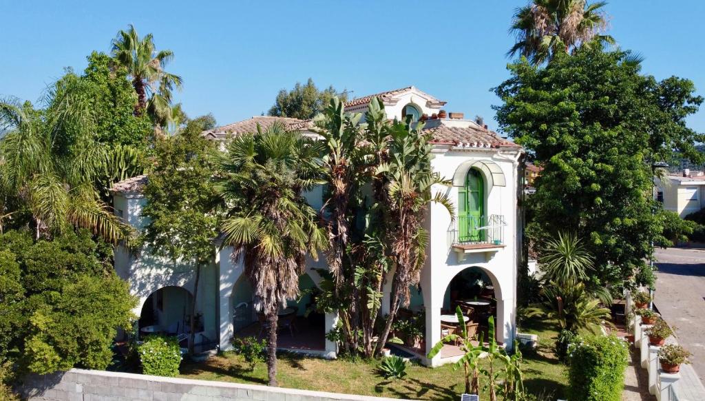 una casa blanca con palmeras delante en Castelletto Verde en Bari Sardo