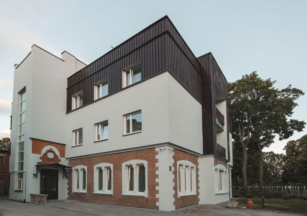an external view of a white building with a black roof at Roze Park Rooms in Liepāja
