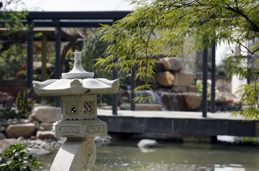 a stone bird feeder sitting in front of a pond at Belgravia Serviced Residence Wuxi in Wuxi