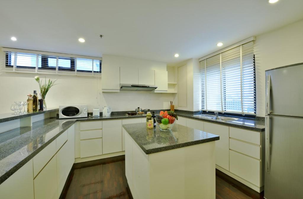 A bright white kitchen with an island, cooktop, microwave, refrigerator, and wide counters.