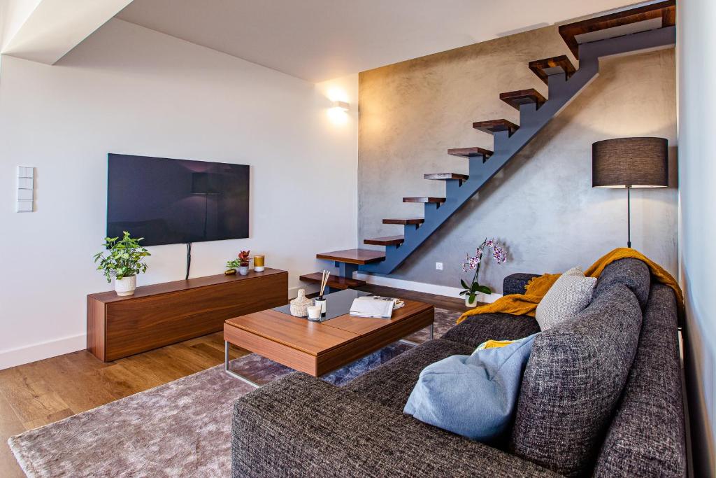 Una sala de estar con un sofá y una escalera. en Equador Penthouse by Olala Homes, en Cascais