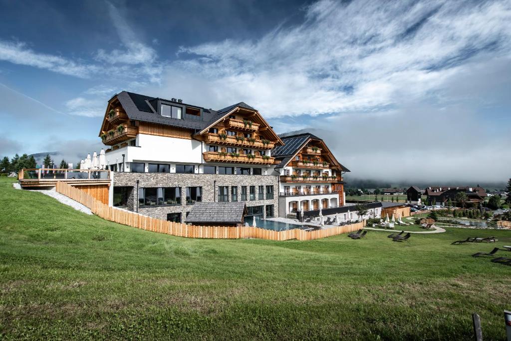 ein großes Gebäude auf einem grünen Feld in der Unterkunft ALMGUT - Mountain Wellness Hotel in Sankt Margarethen im Lungau