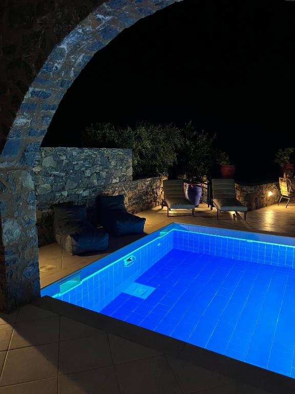 a swimming pool at night with a stone wall at Villa Helios in Elounda