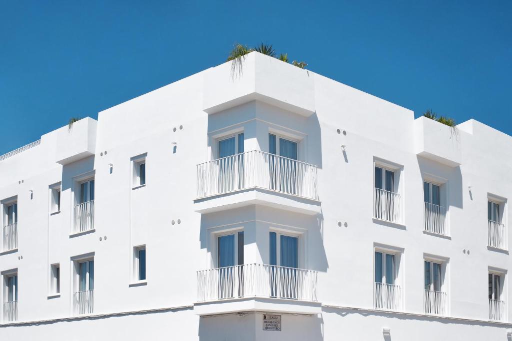 a white building with balconies and a blue sky at Rio Salado Conil Hostal in Conil de la Frontera