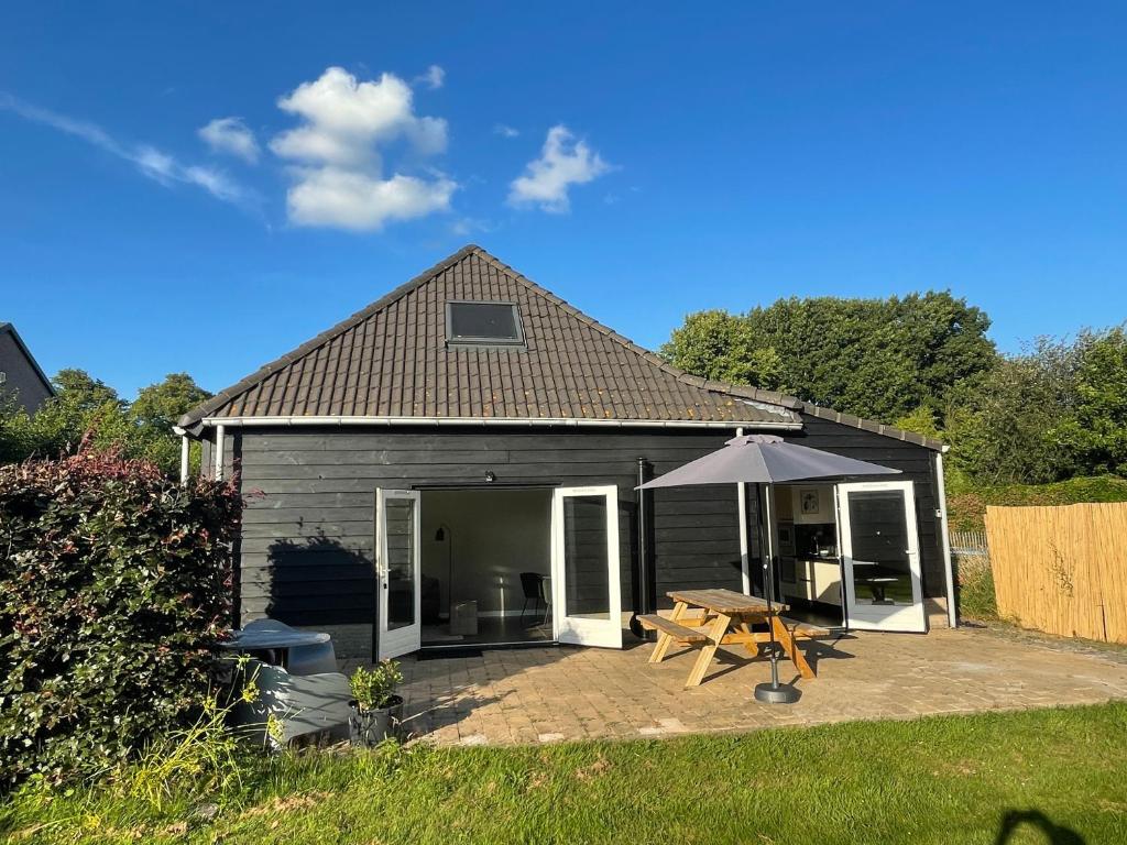 una pequeña casa con una mesa de picnic y una sombrilla en Vakantiehuis FijnDomein - vlak bij de Efteling, en Dongen