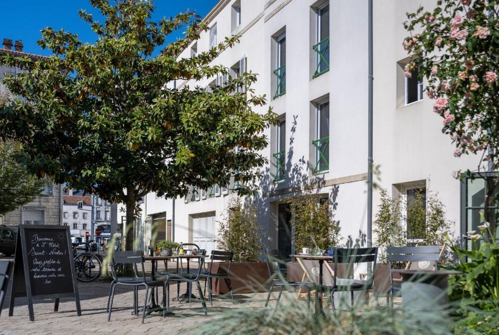 a patio with tables and chairs in front of a building at Hôtel Saint Nicolas in La Rochelle