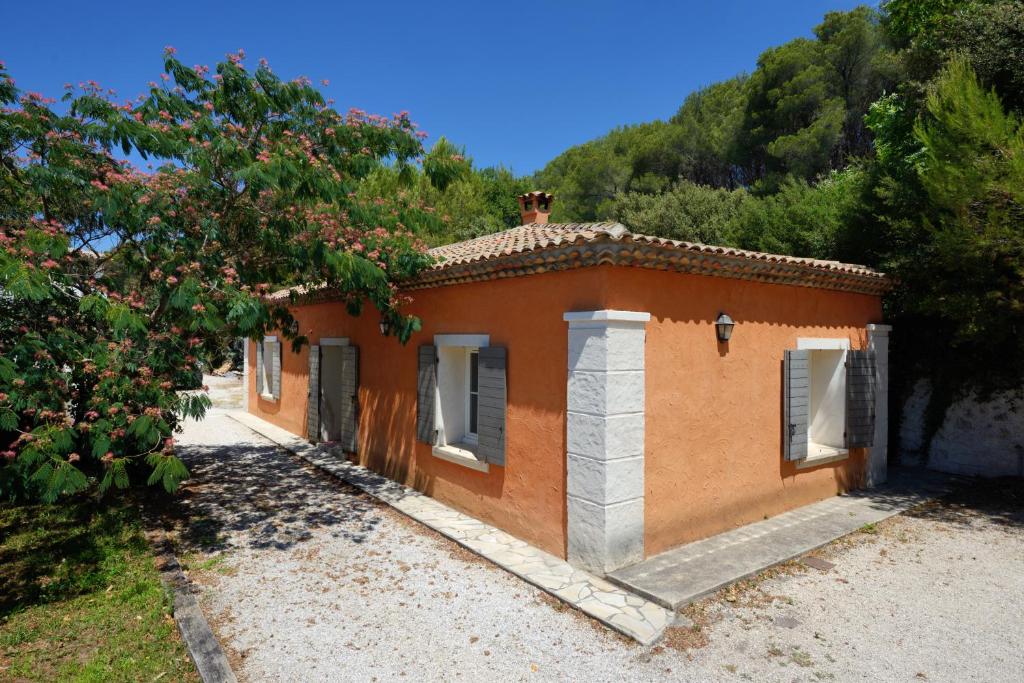 un pequeño edificio naranja en un campo con un árbol en La Petite Maison - Mas des Sous Bois en Ventabren