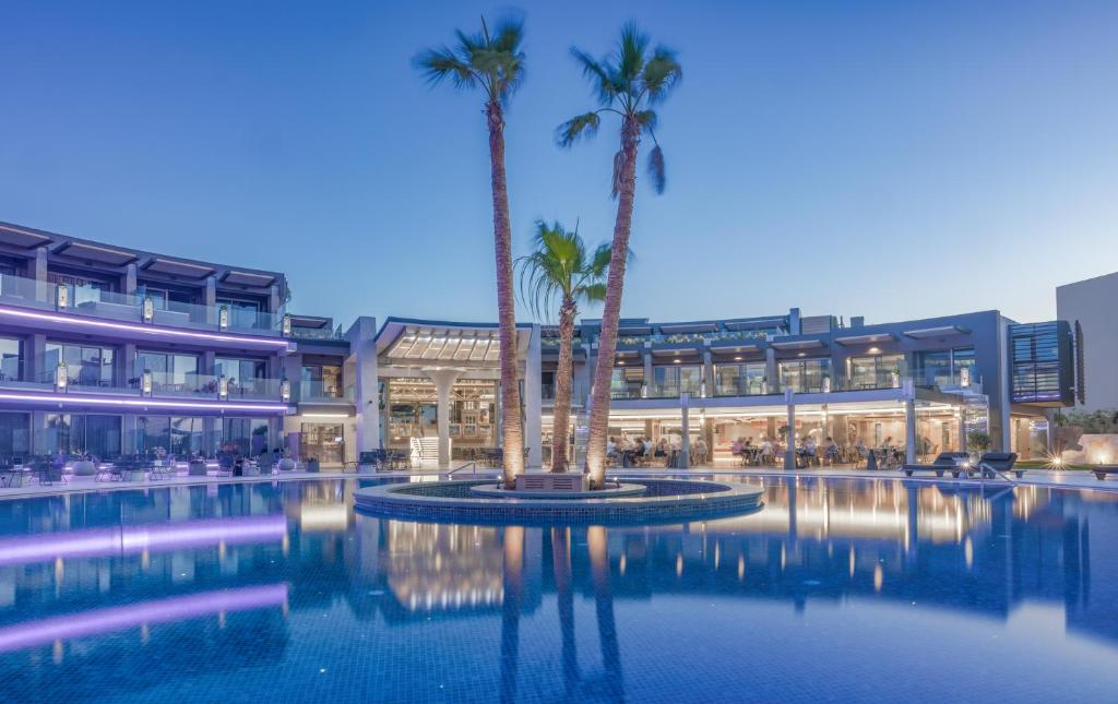 a hotel with palm trees in front of a building at Nautilux Rethymno by Mage Hotels in Rethymno