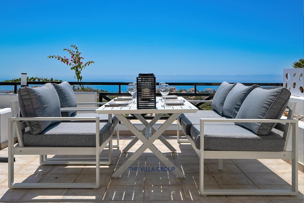 a white table and chairs on a patio with the ocean at Thea Vista Apartment in Pissouri