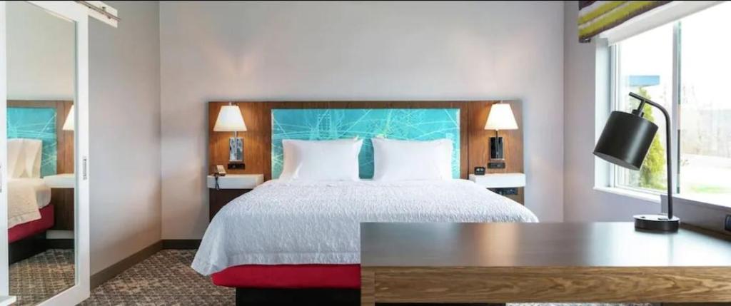 Hampton Inn & Suites Howell في Howell: غرفة نوم بسرير مع طاولة ونافذة