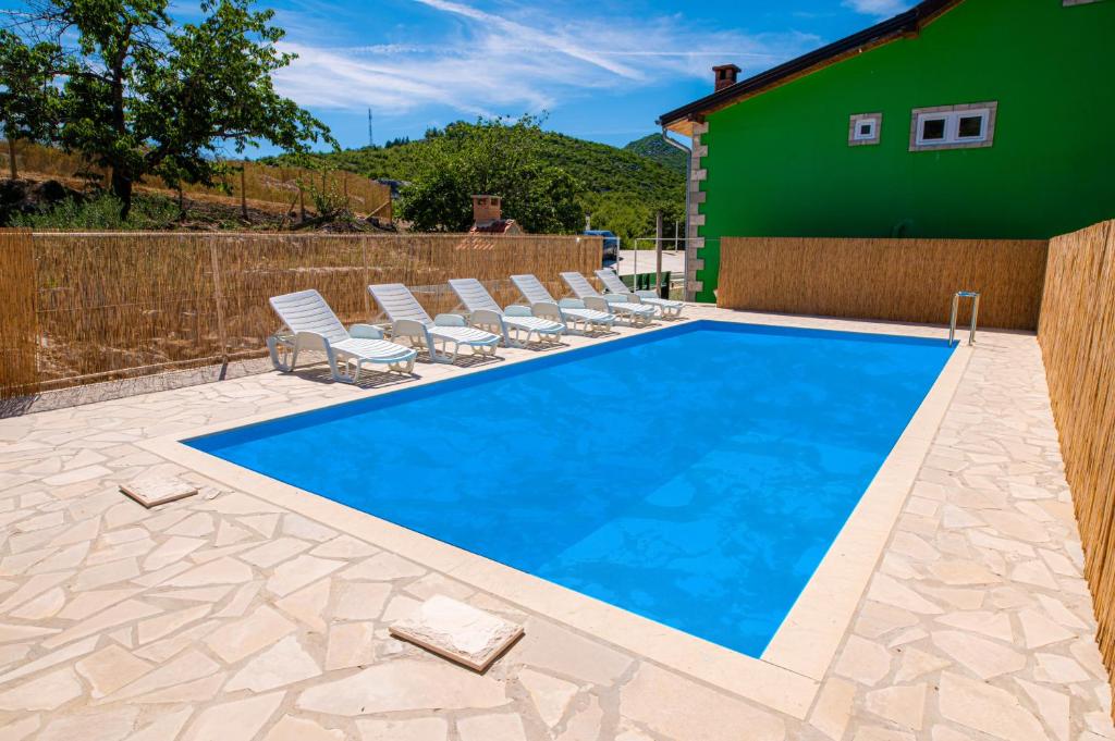 a swimming pool with chairs and a green building at Holiday Home Mediteran in Neum