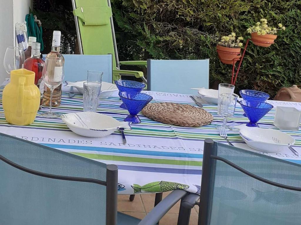 une table avec des verres bleus et des assiettes dessus dans l'établissement Maison de vacances avec terrasse, jardin, garage, animaux acceptés à Royan - FR-1-494-116, à Royan