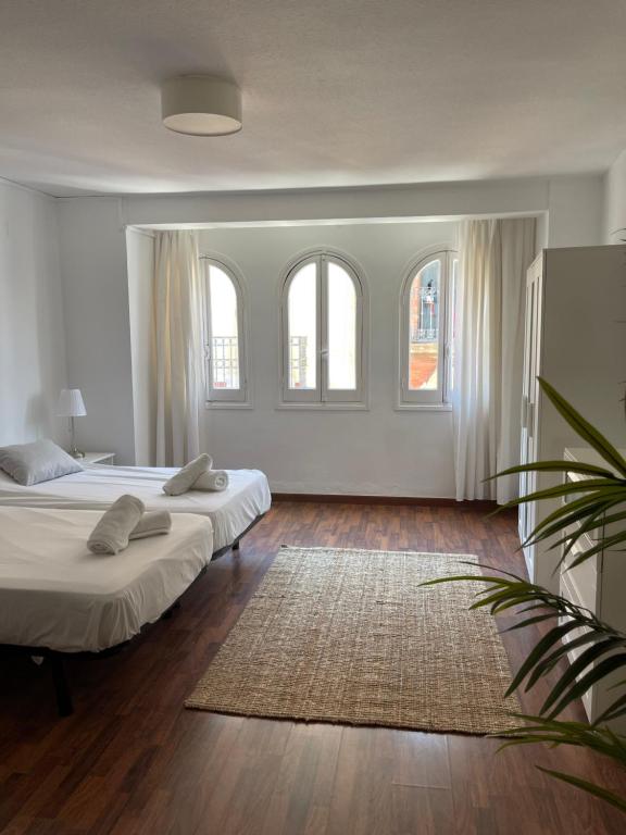 - 2 lits dans une chambre avec 2 fenêtres et un tapis dans l'établissement IRUA APARTAMENTOS, à Ronda
