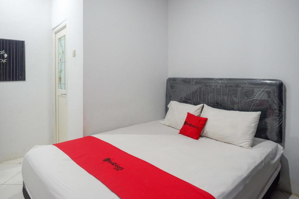 a bed with two red pillows on it in a room at RedDoorz At Jalan Raya Baturaden in Rempawah