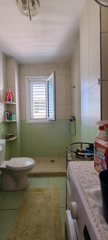 een badkamer met een wastafel, een toilet en een raam bij SleepIn Shkoder in Shkodër