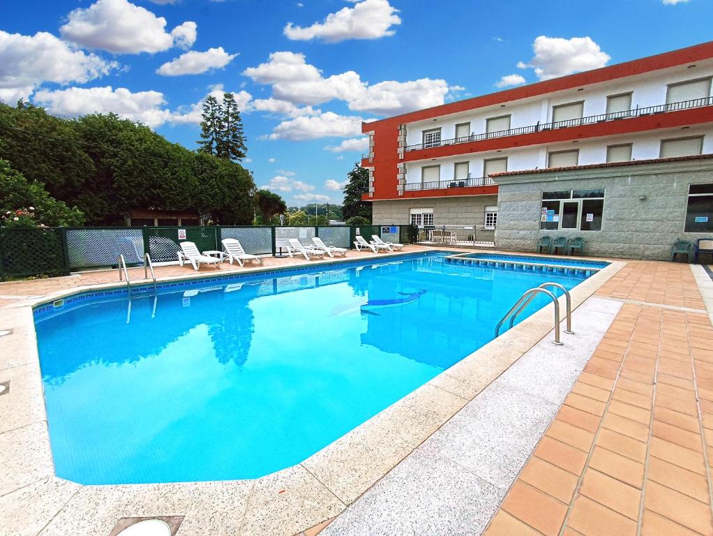 uma grande piscina com cadeiras e um edifício em Hotel Galaico Sanxenxo em Sanxenxo