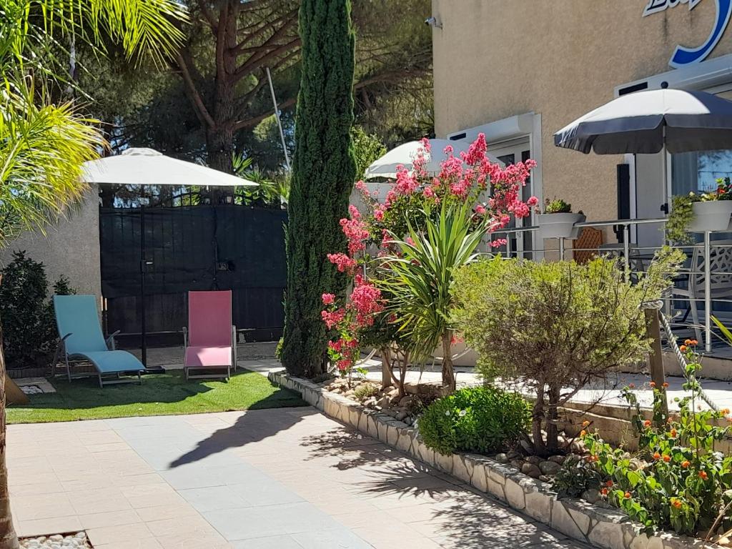 einen Garten mit rosa Blumen und Sträuchern und einem Sonnenschirm in der Unterkunft chambre cocooning in Marseillan