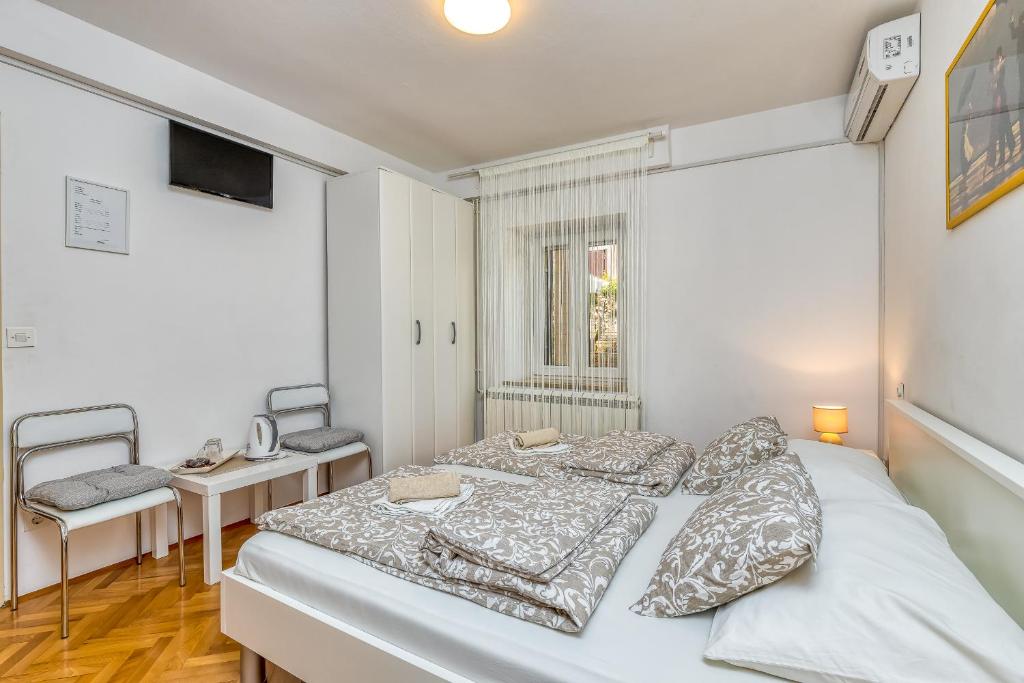 een witte slaapkamer met 2 bedden en een bureau bij Matea Rooms in Funtana