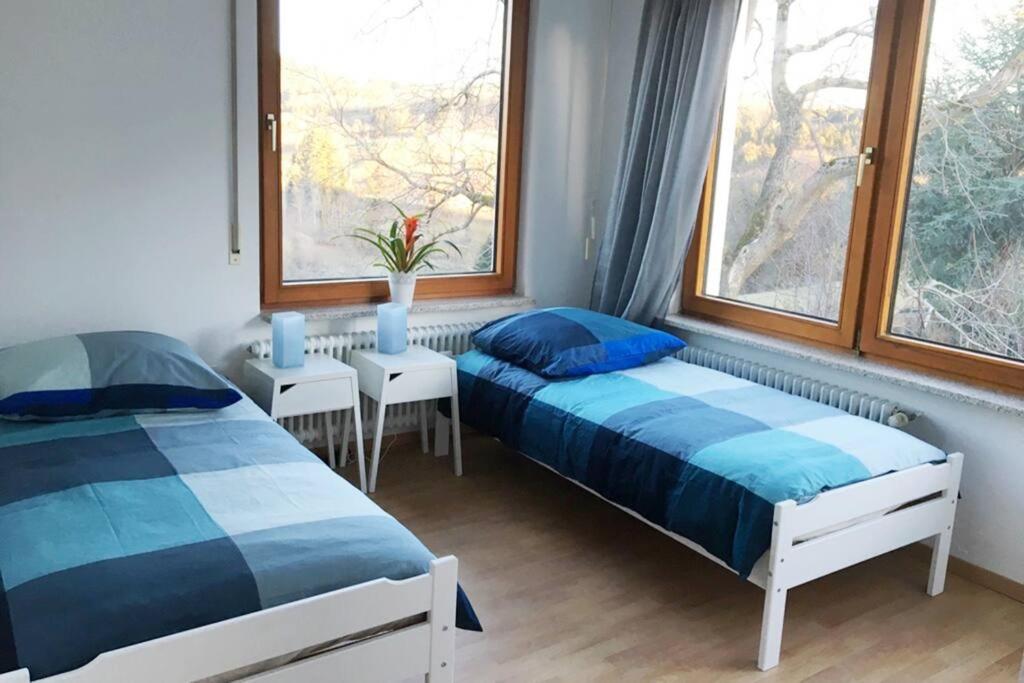 two beds in a room with two windows at Ferienwohnung mit fantastischem Ausblick & SmartTv in Waldstetten