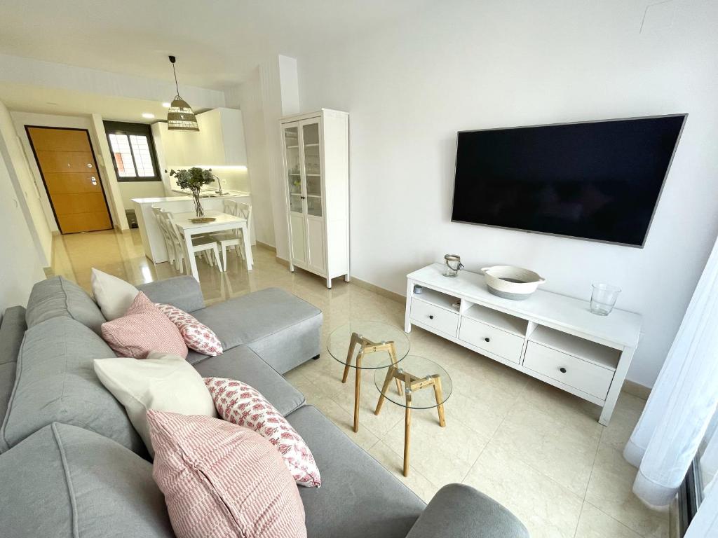 Il comprend un salon doté d'un canapé gris et d'une télévision à écran plat. dans l'établissement El Arrecife - Apartamento a 2 minutos de la playa en El Puerto de Santamaría, à El Puerto de Santa María