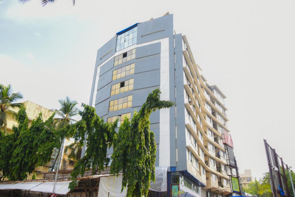 un edificio alto con árboles delante de él en Kings International Juhu en Bombay