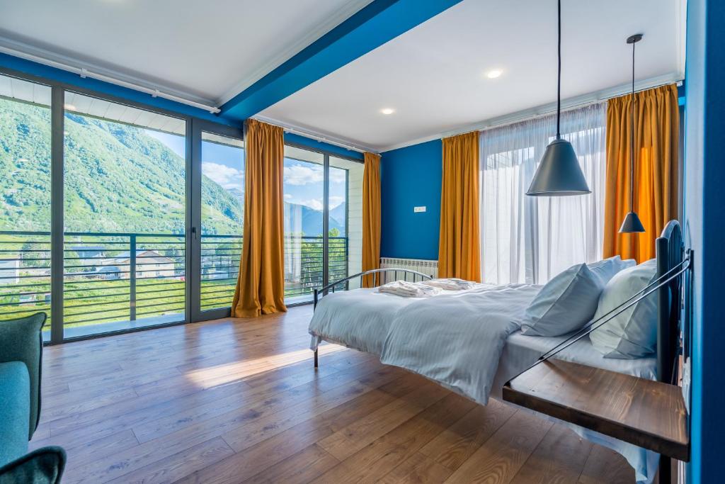 a bedroom with a bed and large windows at Hotel Darchi Kazbegi in Stepantsminda