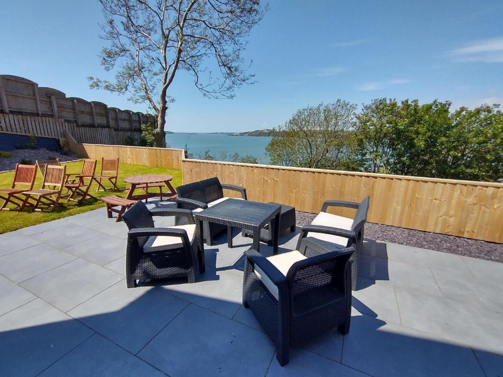 a patio with a table and chairs and a picnic table at Martello View - 3 Bedroom Holiday Home - Llanreath in Pembroke Dock