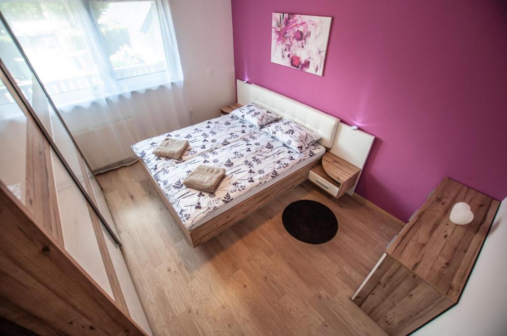 Dormitorio pequeño con cama y pared púrpura en Apartments Jelka, en Bohinj