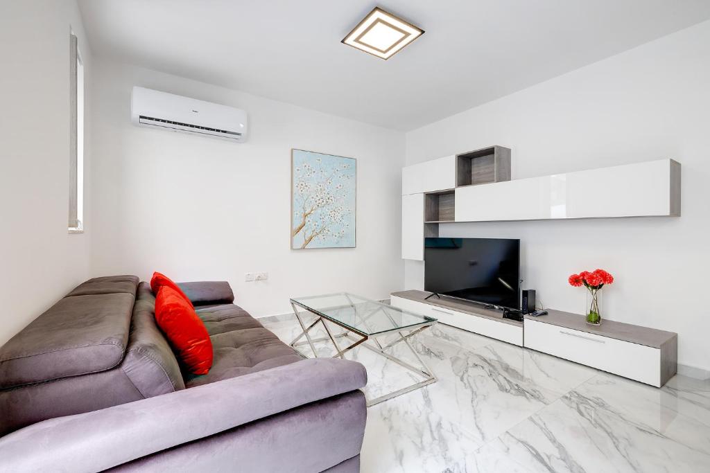 un soggiorno con divano e TV di Cosy Apartment steps to St George's Bay a San Giuliano