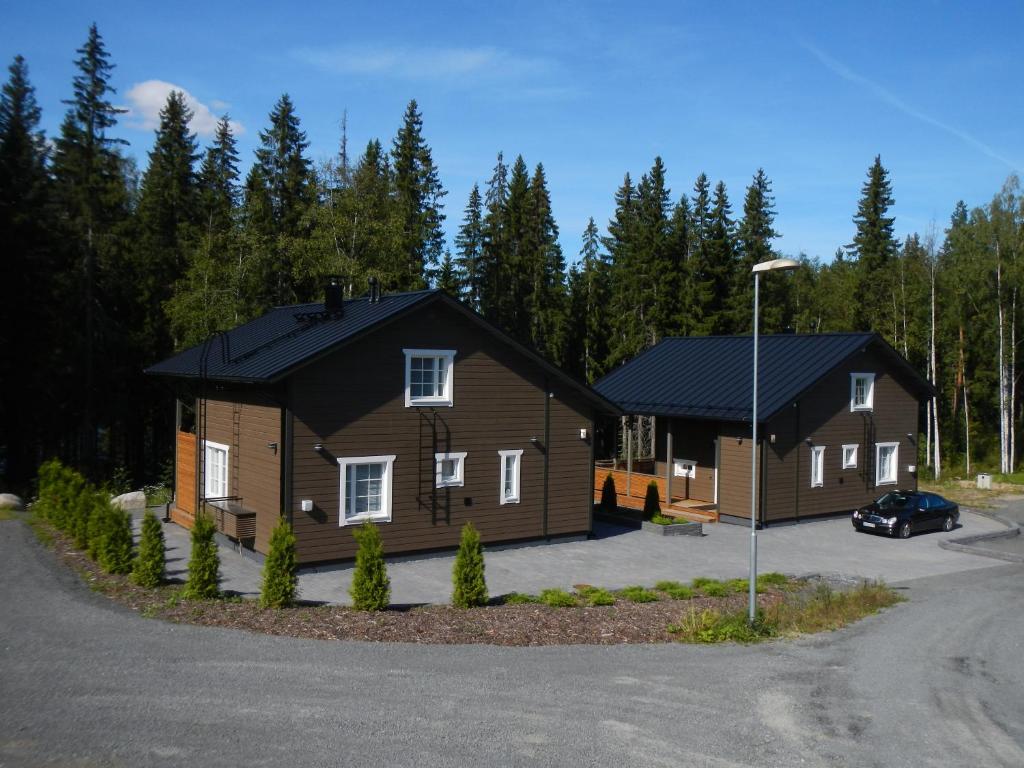 a couple of large wooden homes in a parking lot at Himos Villa Nummenranta 1 in Jämsä