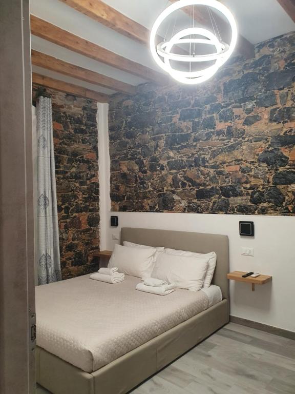 - une chambre avec un lit et un mur en briques dans l'établissement 5 Terre Station Rooms, à La Spezia