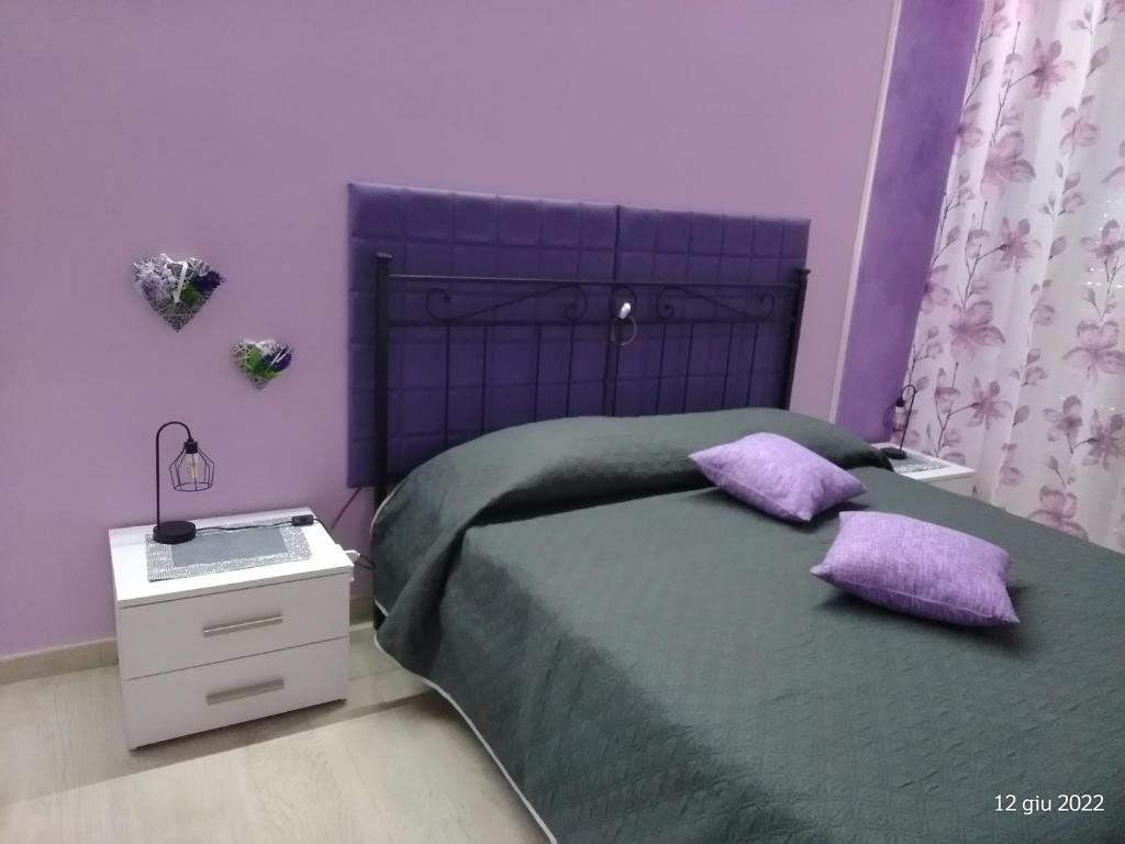 purpurowa sypialnia z łóżkiem o fioletowych ścianach w obiekcie ALLOGGIO VIOLA nel CUORE DI SORIANO w mieście Soriano nel Cimino