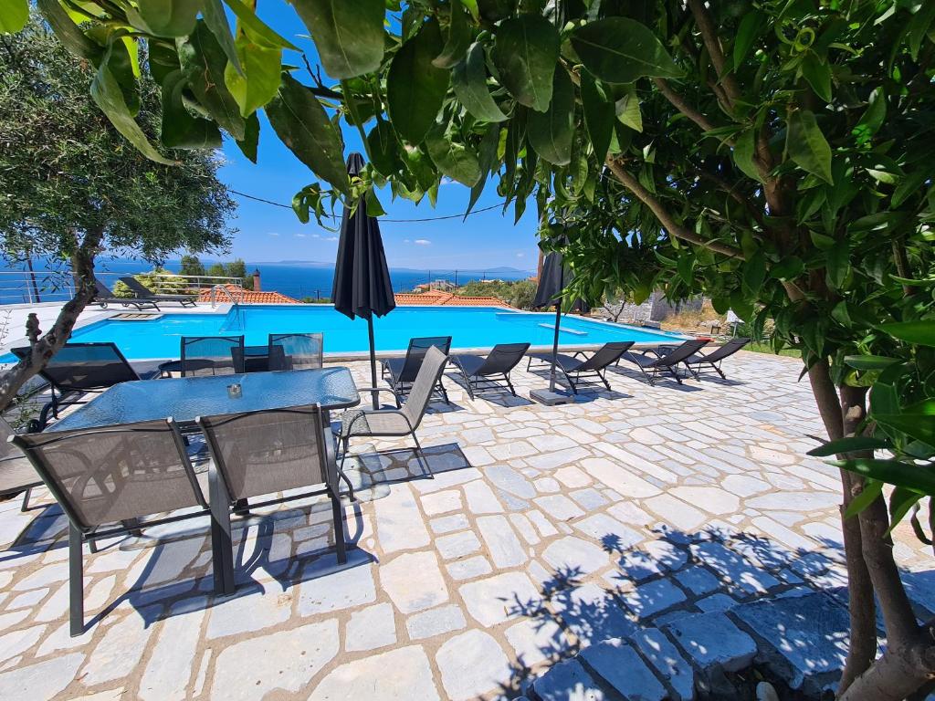a patio with chairs and a table and an umbrella at Leopolis Villas in Stoupa