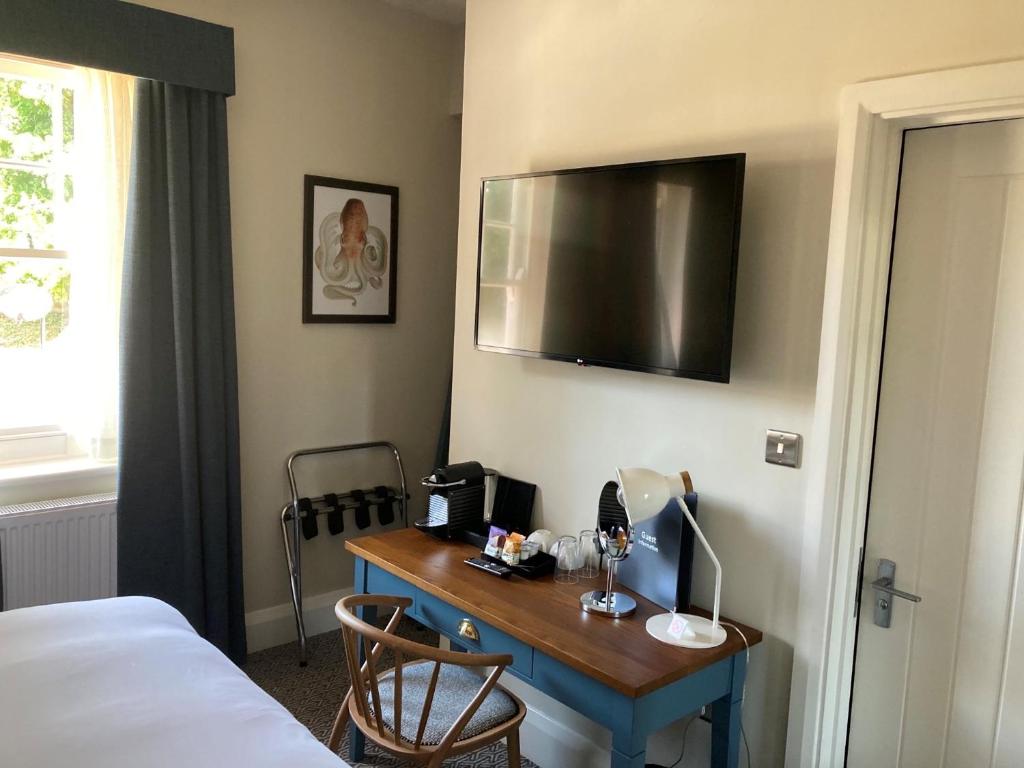 a room with a desk with a bed and a television at Downs Hotel in Stanmer