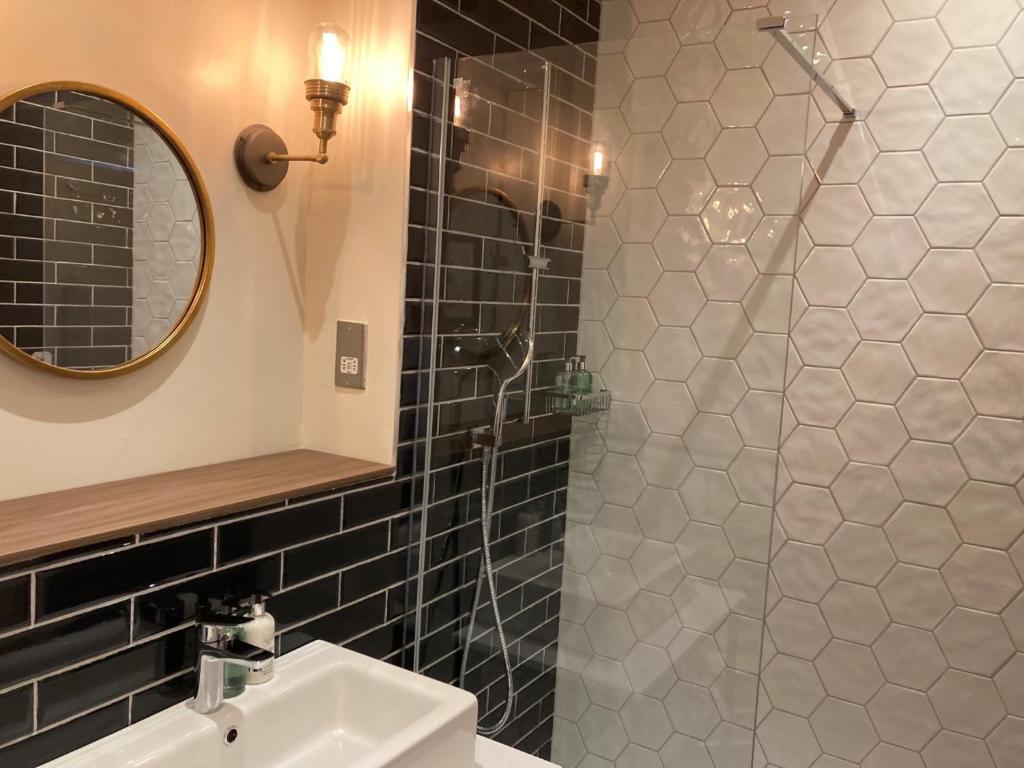 a bathroom with a shower with a sink and a mirror at Downs Hotel in Stanmer