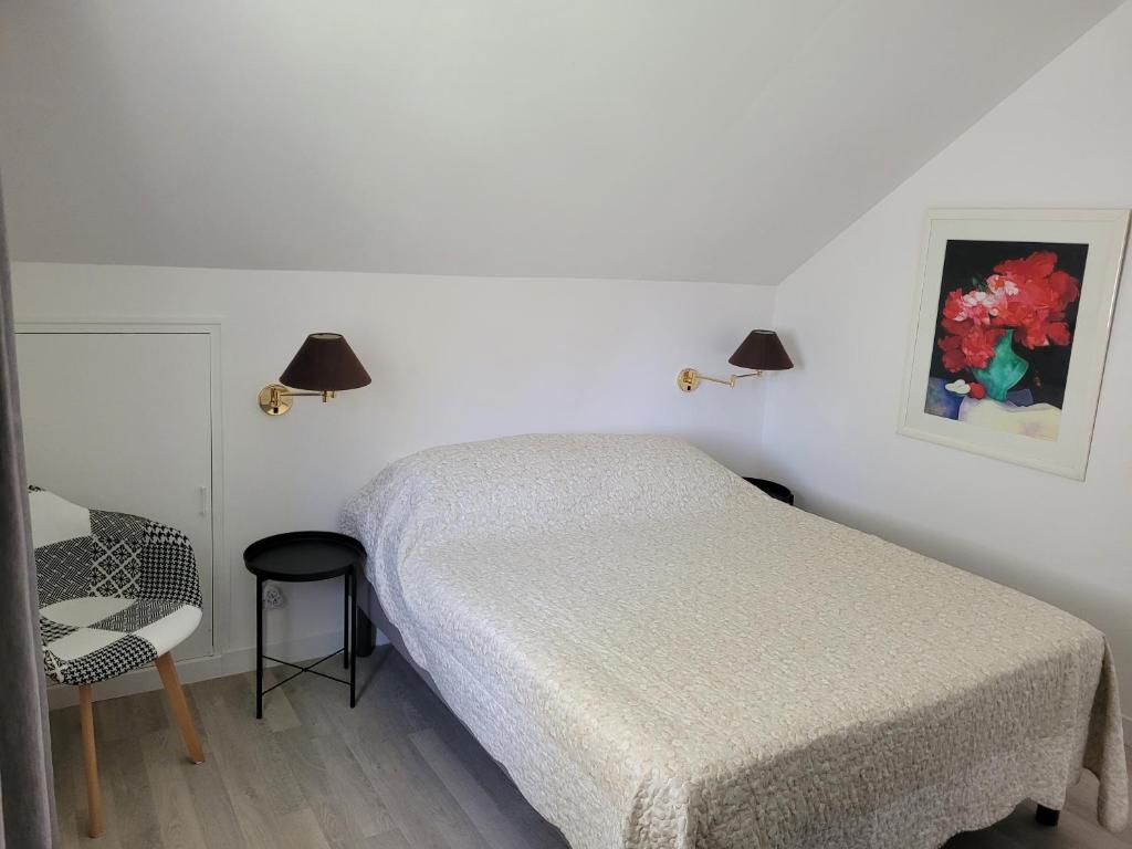 um quarto branco com uma cama e uma cadeira em La maison d'Hera em Saint-Yrieix-la-Perche