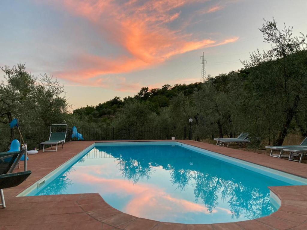 a swimming pool with a sunset in the sky at Agriturismo "Crocino in Chianti" in Gaiole in Chianti