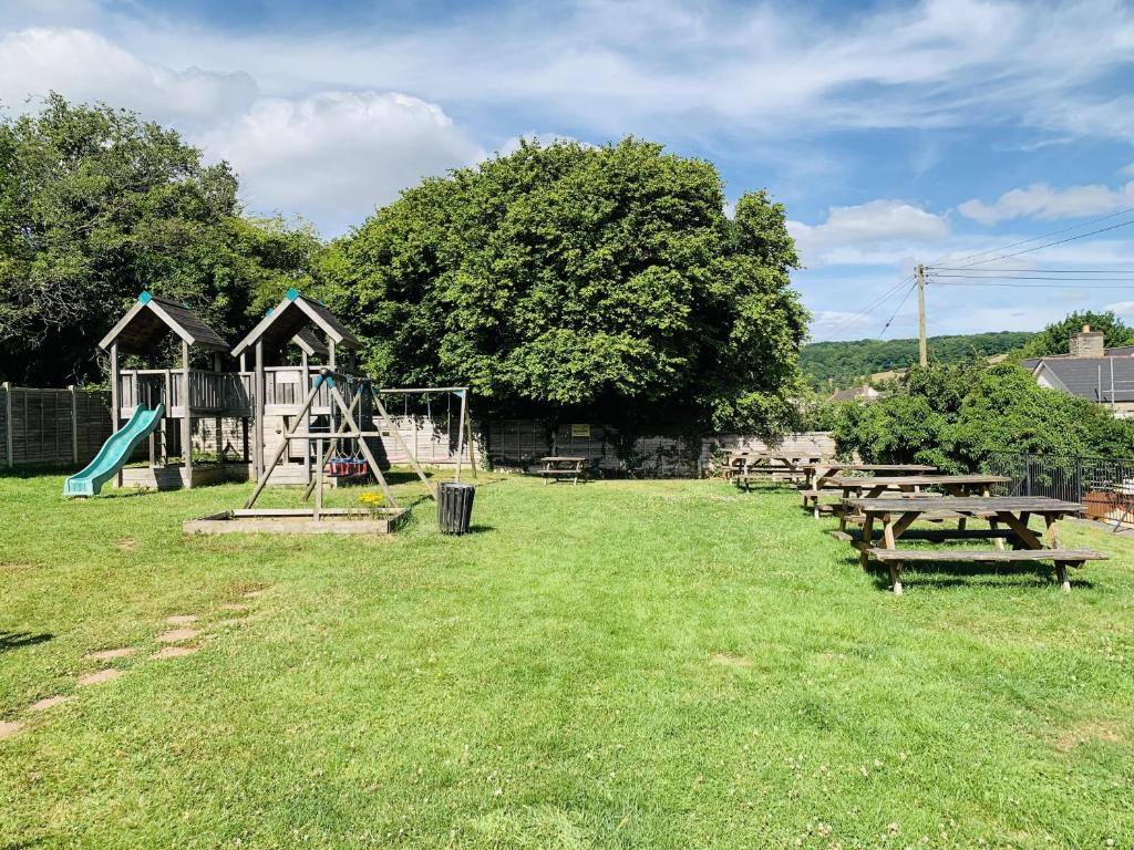 un parque con mesas de picnic y un parque infantil en The Yew tree at Longhope, en Longhope