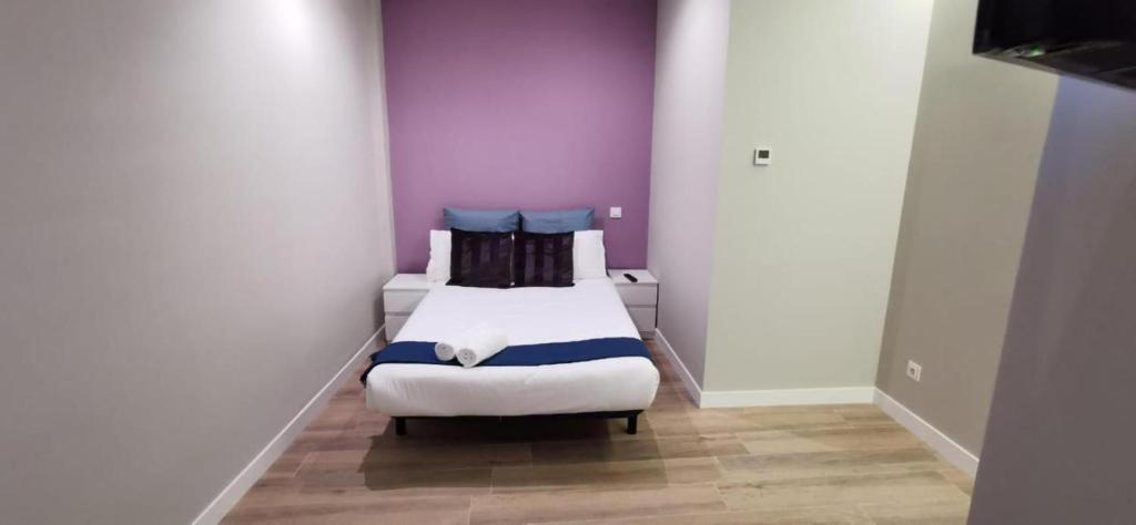 Kleines Zimmer mit 2 Betten und lila Wänden in der Unterkunft Apartamentos Sol Madrid in Madrid