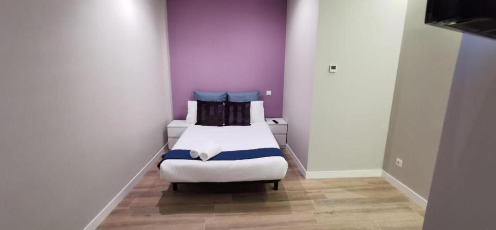 a small room with two beds with purple walls at Apartamentos Sol Madrid in Madrid