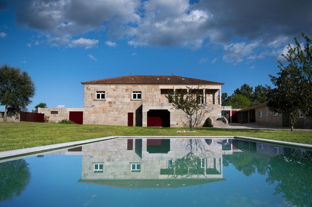 een oud stenen huis met een zwembad ervoor bij Countryside Villa with Nature & Pool - 'Casa dos Vasconcelos' in Chaves