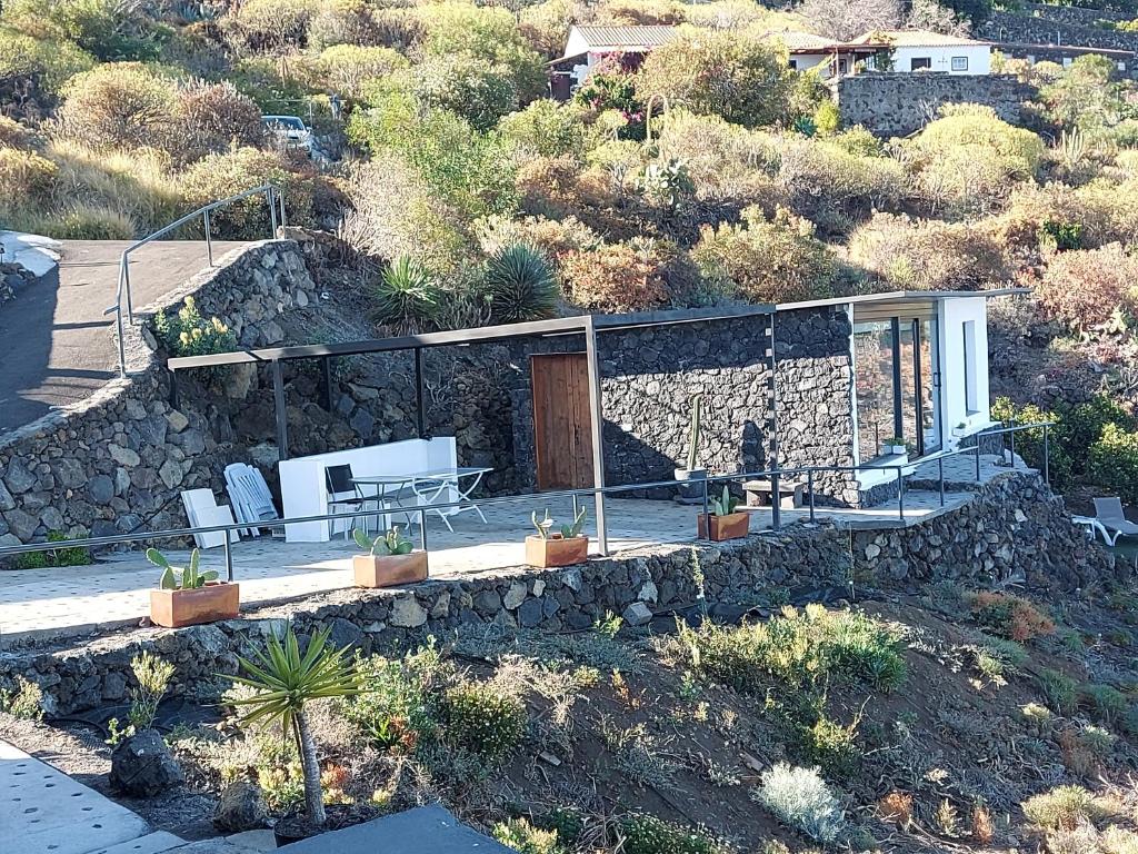 een huis op een heuvel met een stenen muur bij Bungalowmirador in Fuencaliente de la Palma