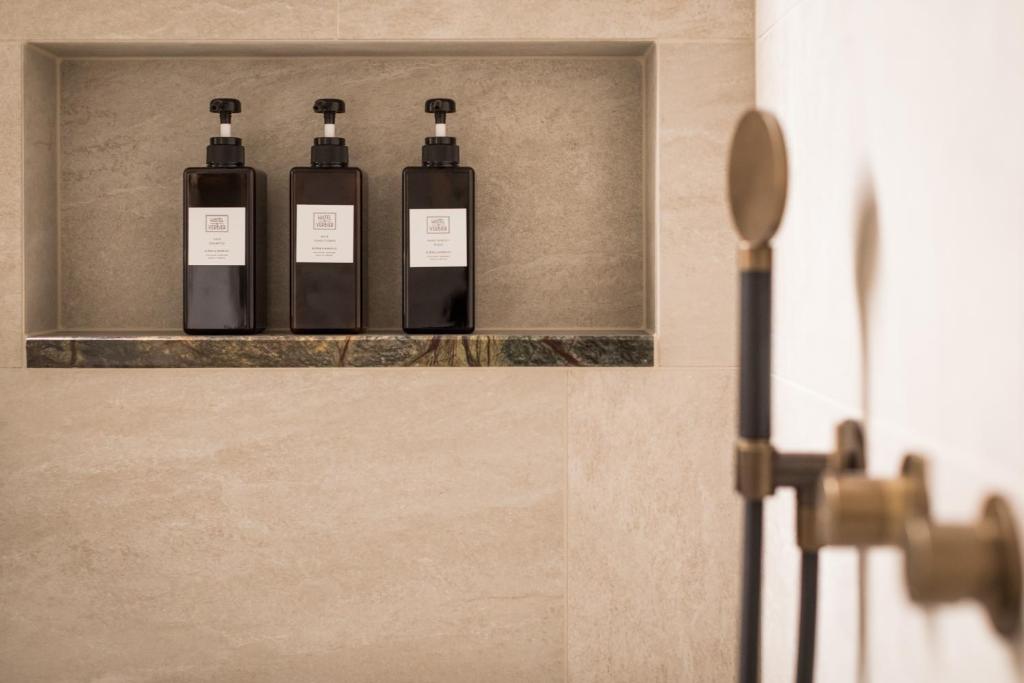 three bottles of soap sitting on a shelf in a bathroom at Hôtel de Verbier SUP in Verbier