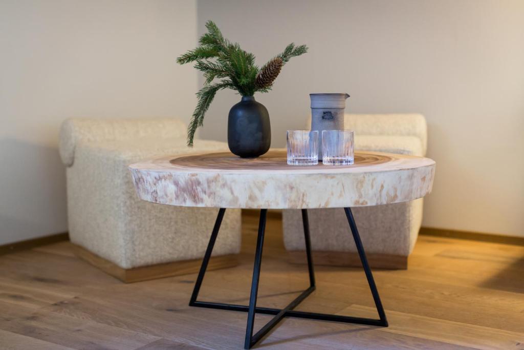 a table with two glasses and a vase on it at Hôtel de Verbier SUP in Verbier