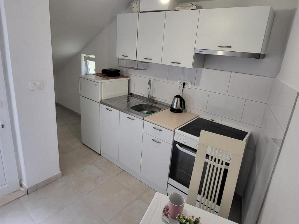 a small kitchen with white cabinets and a stove top oven at Apartment Dora in Dubrovnik