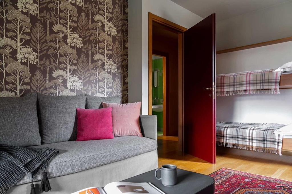 a living room with a gray couch with pink pillows at Hotel Tremoggia in Chiesa in Valmalenco