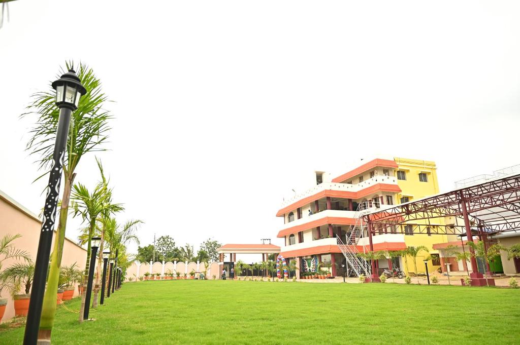 um campo verde ao lado de um edifício com palmeiras em BASANTA CONVENTION em Balasore